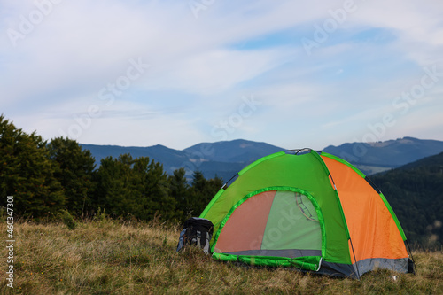 Color camping tent on grass in mountains, space for text