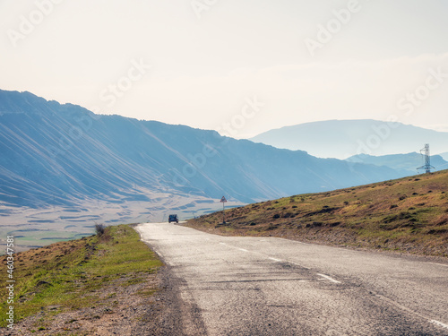 Hot asphalt road through the hills and mountains. Turn on an empty mountain road. Old cracked asphalt mountain road in Dagestan.