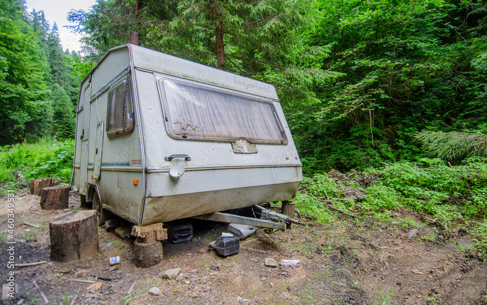 Abandoned travel trailer in the meadow with forest on background. Romania Transilvania 