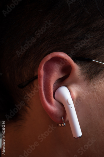 Close up of caucasian man ear with a white wireless earphone