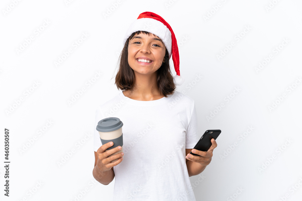Young mixed race woman celebrating Christmas isolated on white background holding coffee to take away and a mobile Young mixed race woman celebrating Christmas isolated on white background holding coffee to take away and a mobile