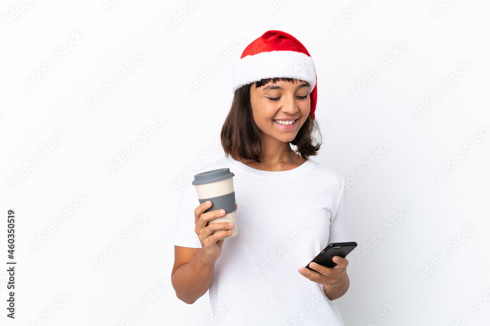 Young mixed race woman celebrating Christmas isolated on white background holding coffee to take away and a mobile Young mixed race woman celebrating Christmas isolated on white background holding coffee to take away and a mobile