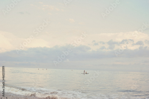 Black Sea in Abkhazia. Small figures of surfers. Blue pastel sunset. Rest on the sea