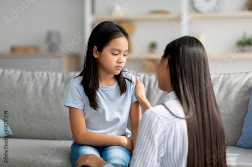 Slika na platnu Young korean mother comforting upset girl, talking and consoling her at home, co