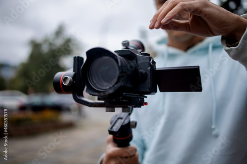 Young Professional videographer holding professional camera on 3-axis gimbal stabilizer. Pro equipment helps to make high quality video without shaking. photo