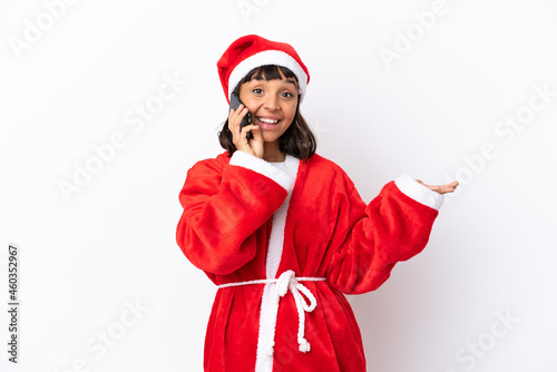 Young mixed race woman disguised as Santa Claus isolated on white background keeping a conversation with the mobile phone with someone