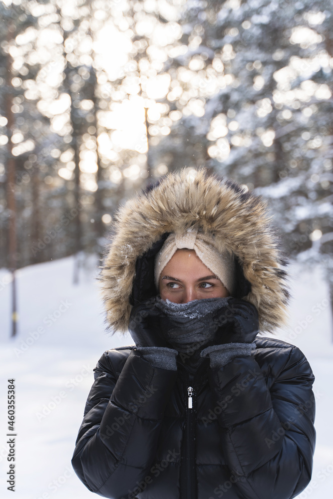 Young woman wearing down jacket with a hoodie during cold winter day