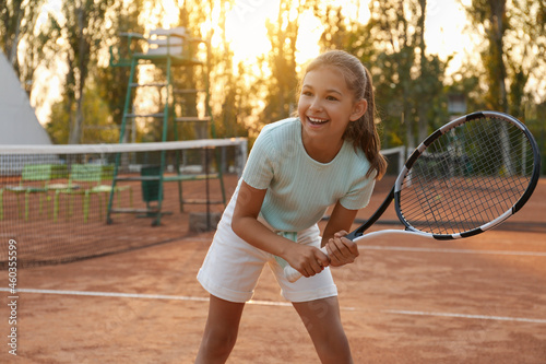 Foto Cute little girl playing tennis on court outdoors