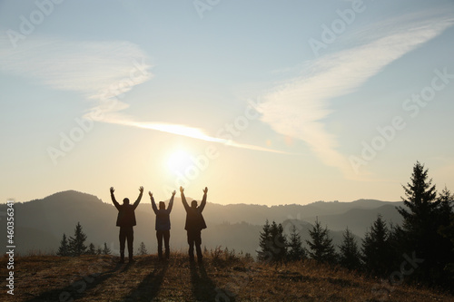 Group of people enjoying sunrise in mountains, back view. Space for text