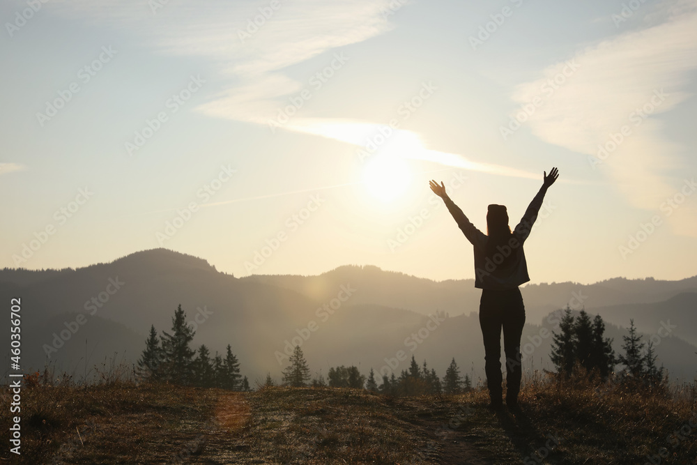 Silhouette of woman at sunrise in mountains, back view. Space for text Silhouette of woman at sunrise in mountains, back view. Space for text