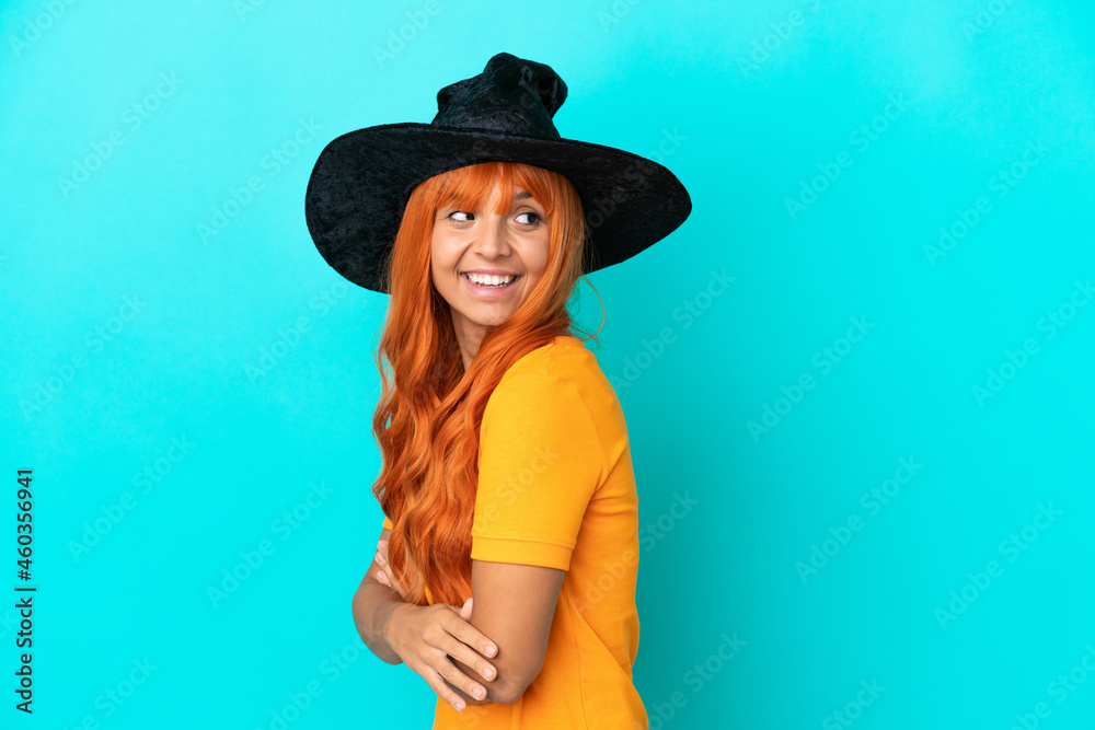 Young woman disguised as witch isolated on blue background with arms crossed and happy Young woman disguised as witch isolated on blue background with arms crossed and happy