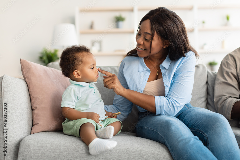 African American mom playing with her cute baby on couch