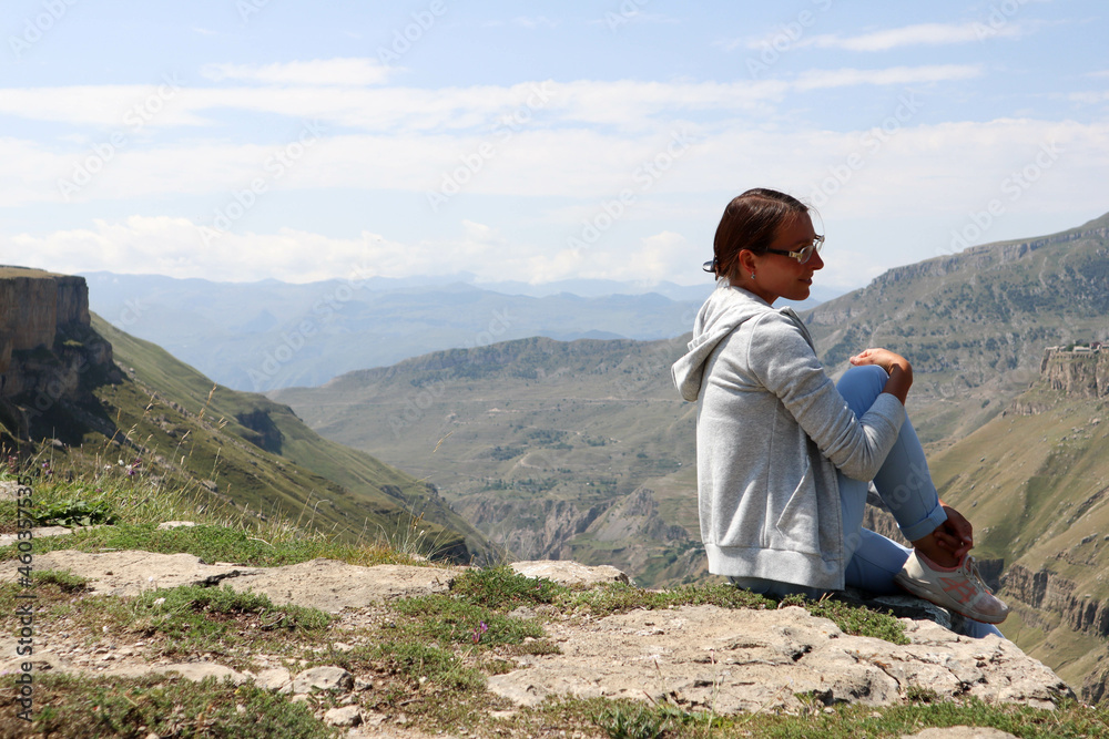 woman person sitting on the edge of the canyon with beautiful mountains on background