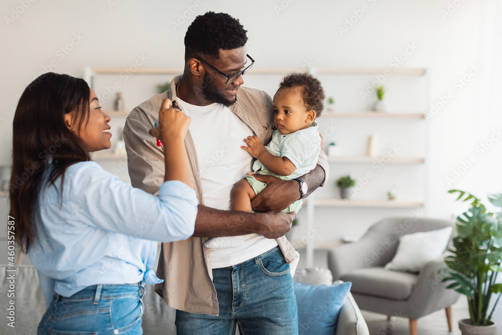 Happy black parents holding baby pointing at window Happy black parents holding baby pointing at window