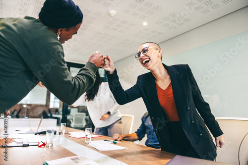 Young businesspeople fist bumping each other before a meeting photo