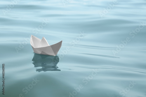 White paper boat floating on water surface, space for text