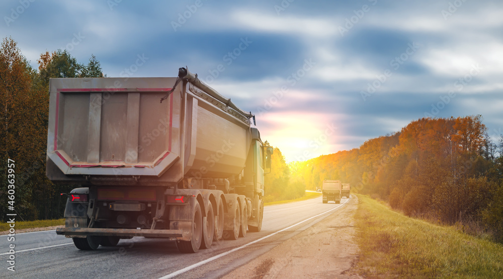a truck is driving along the highway at sunset, a cargo transportation concept