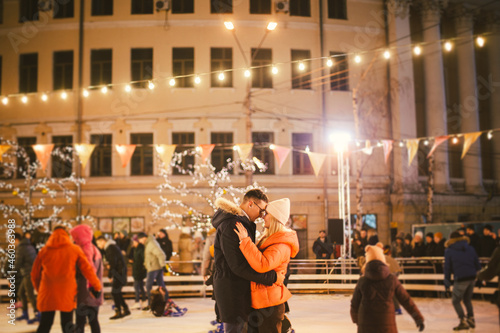 Beautiful Couple Ice Skating In City Centre. Young couple skating at a public ice skating rink outdoors. Theme ice skating rink and loving couple. Amazing winter holiday. Saint Valentine's Day