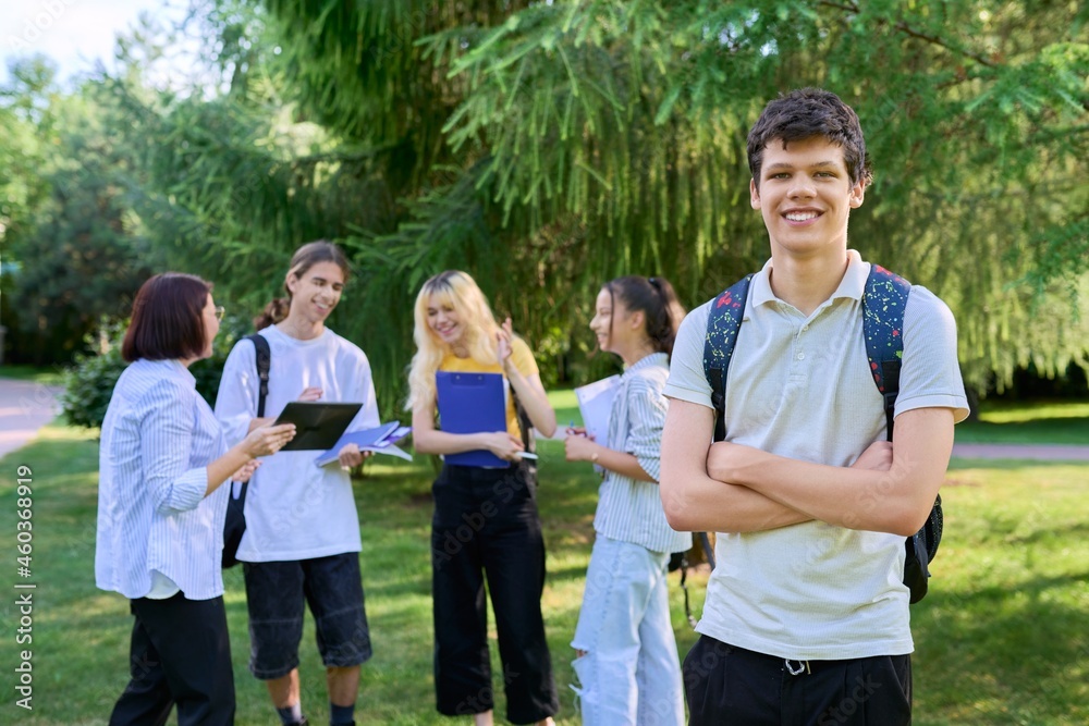 Portrait of male student in park campus, group of teenagers with teacher background Portrait of male student in park campus, group of teenagers with teacher background