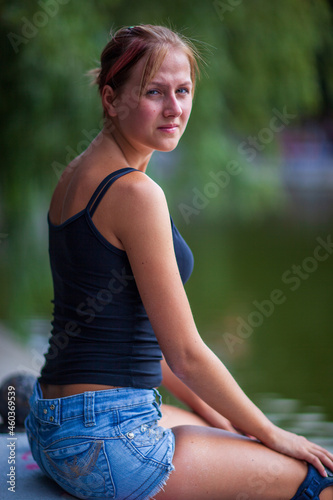 Young blonde happy girl resting in the park on a warm summer day photo