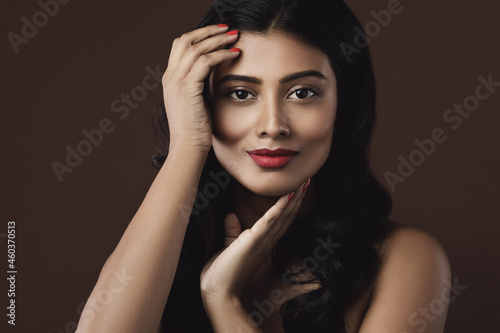 Indian woman with beautiful makeup and hairstyle on brown background