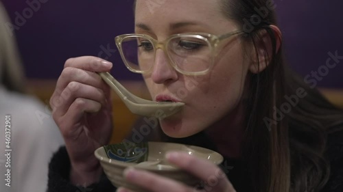 This video shows a caucasian woman drinks hot broth asian soup from a bowl.