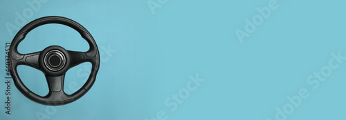 Fotografie, Tablou Black steering wheel on light blue background, top view with space for text
