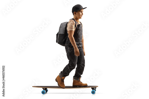 Full length profile shot of a boy with a backpack riding a longboard