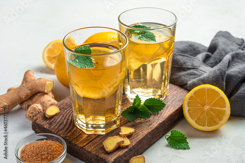 Two glasses of healthy ginger tea with lemon on a gray background. Side view, close-up.