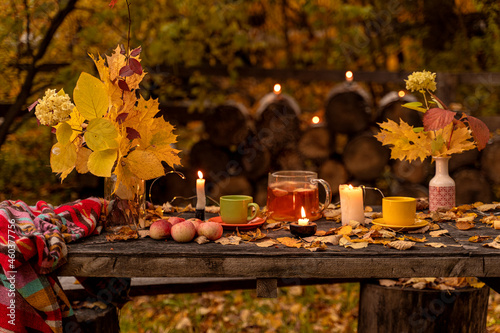 Autumn still life with tea and apples among yellow leaves