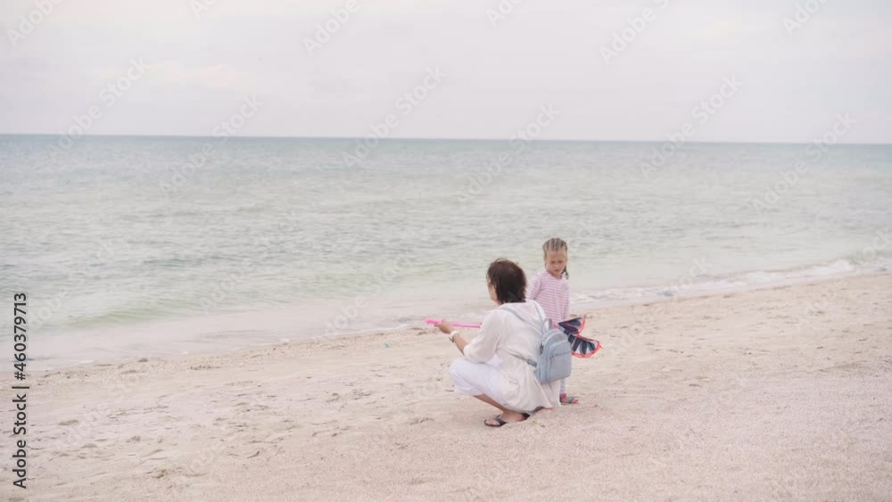 Mother With Little Child Blowing Soap Bubbles On Sea Beach Traveling with one Children Family Summer Vacation. Mom And Little Girl Playing Outdoors