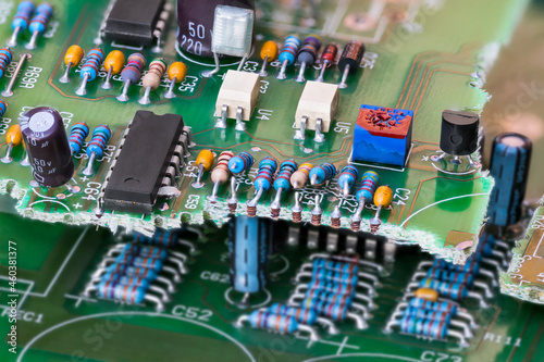 Closeup of electronic waste of broken green printed circuit board with through-hole components technology. Resistors, capacitors or optocouplers and chips. E-waste recycling in electrical engineering. photo