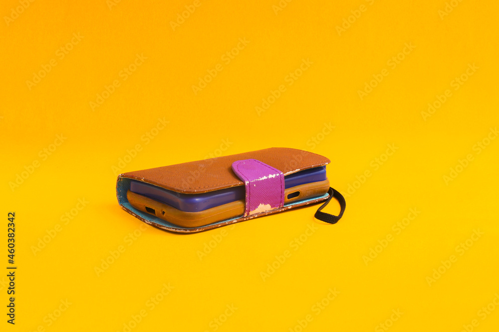 Old used brown phone case isolated on orange background