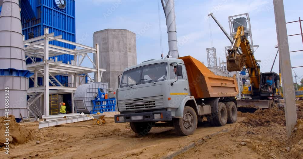 At the construction site where a new, modern plant is being built, the bulldozer does earthworks and loads the drive up truck At the construction site where a new, modern plant is being built, the bulldozer does earthworks and loads the drive up truck