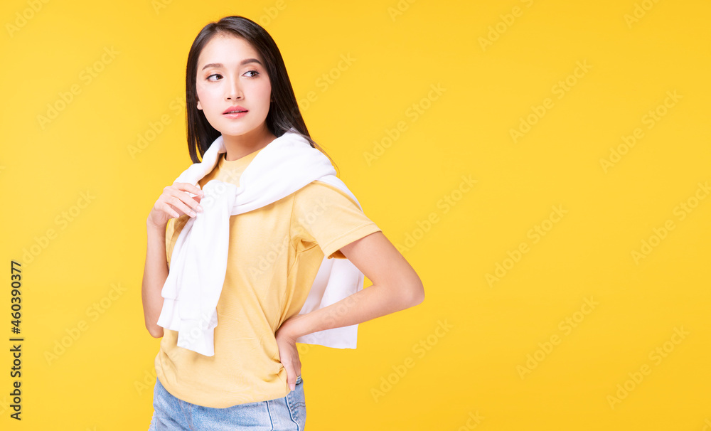 Lifestyle relax in winter season concept. Positive Asian woman wear casual clothing with white sweater around her shoulder while standing arms crossed over isolated against yellow background. Lifestyle relax in winter season concept. Positive Asian woman wear casual clothing with white sweater around her shoulder while standing arms crossed over isolated against yellow background.