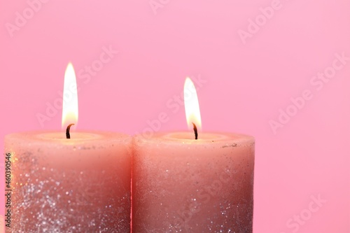 Candles. Burning candles on a pink background. Festive shiny candles. Flame candles close-up.