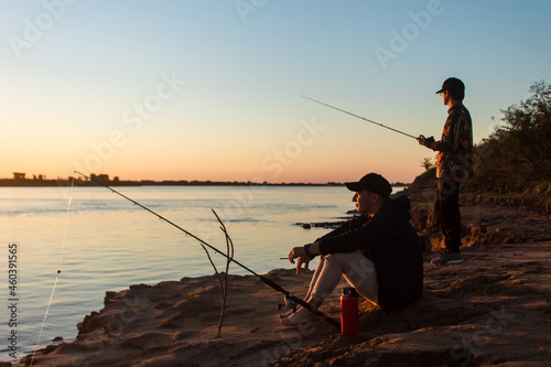 Young friends fishing on the shore of the river. Fishing friends.