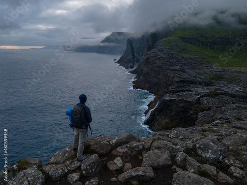 Beautiful aerial view of a tourist watching the B  sdalafossur waterfall and Tr  lan  pan magnificent landmarks in the Faroe Islands