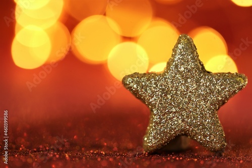 Christmas and New Years season. Shiny decorative star on red glitter background with shining bokeh. Christmas festive red background