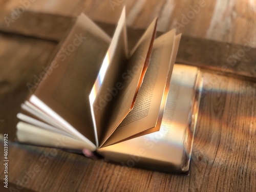 Opened book with fanned pages on a barn door with rays of sunshine.