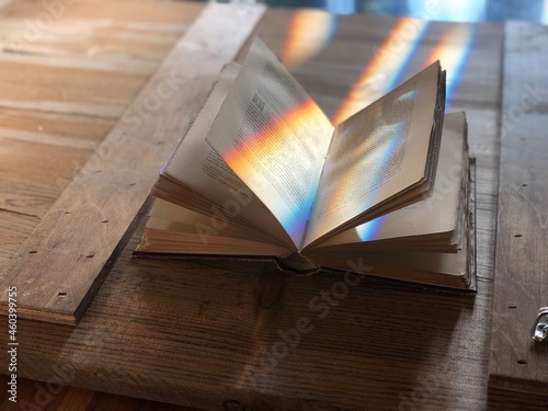 Old open book with fanned pages on a barn door with rays of sunshine.