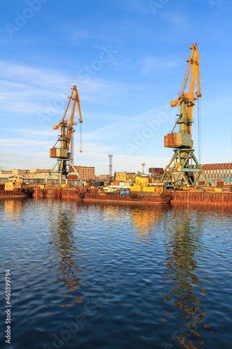Cargo seaport. View of old harbor cranes and rusty ships near the pier. Sea port in the Arctic. Industry and infrastructure in the Far North of Russia. Beringovsky, Chukotka, Siberia, Russia.