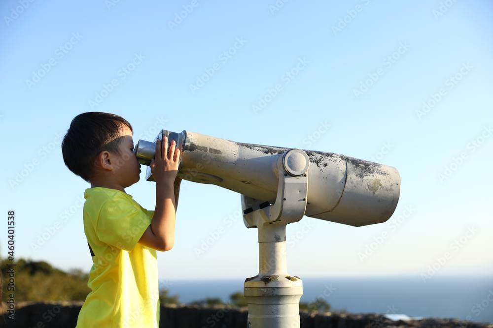 望遠鏡で、小田原の海を見る男の子。