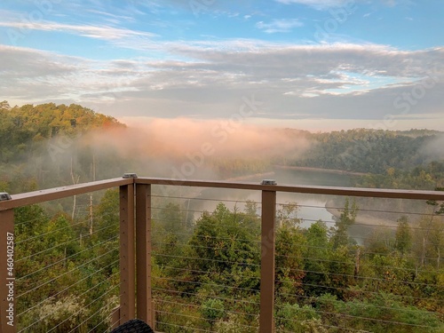Sky with clouds and fog over a river in the distance from a deck.