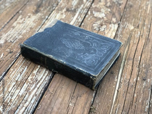 Old black bible on a wooden deck.