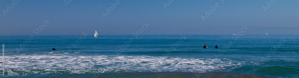 Fototapeta premium Surfers and Sailboat in the Pacific Ocean near Ventura California United States