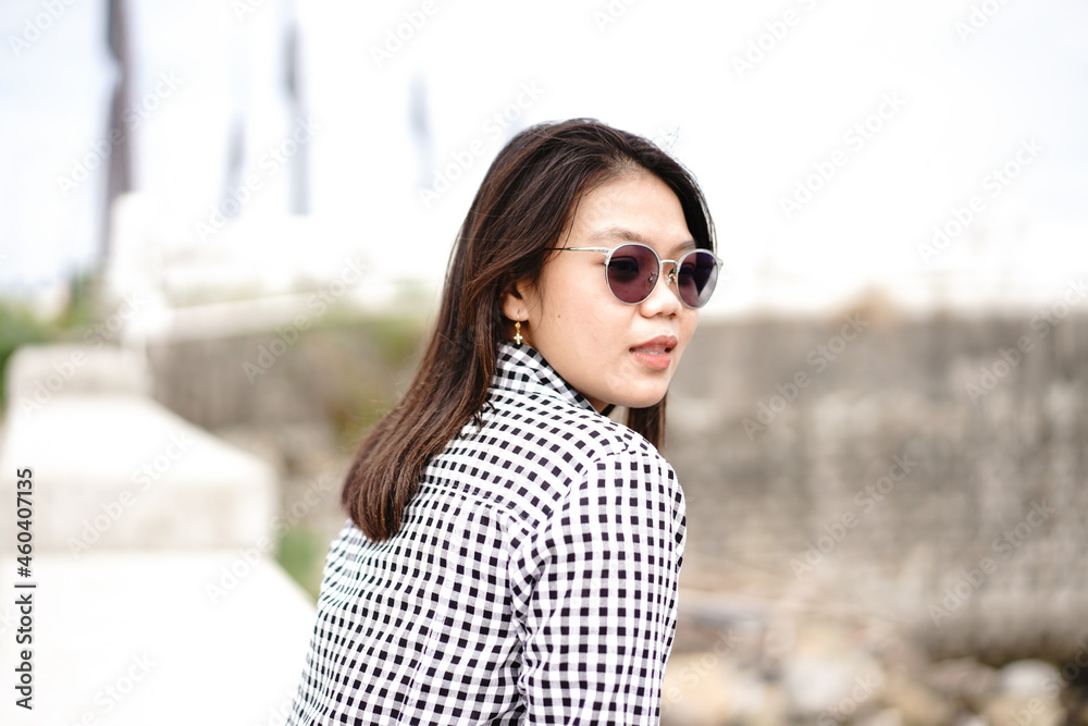 Young Beautiful Asian Woman Wearing Plaid Shirt And Blue Jeans Posing Outdoors Young Beautiful Asian Woman Wearing Plaid Shirt And Blue Jeans Posing Outdoors