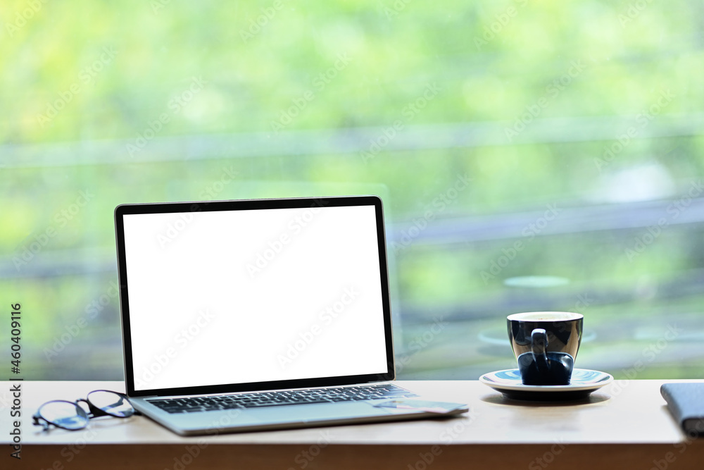 Computer laptop, eyeglasses and cup of coffee on wooden table near glass window. Computer laptop, eyeglasses and cup of coffee on wooden table near glass window.