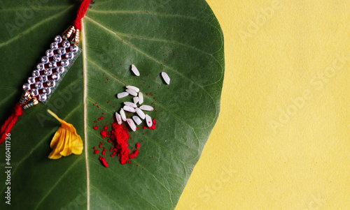 Rakhi Raksha Bandhan bhai dooj bhaiya dooj on on green banyan tree leaf on yellow background photo