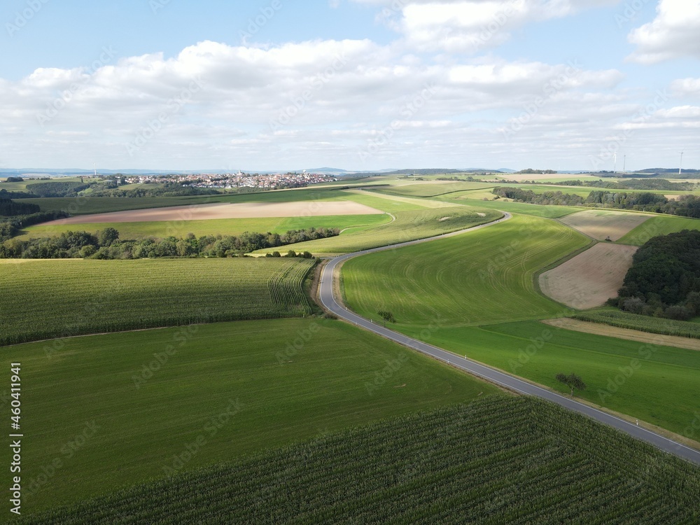 Aerial view of asphalt road between agriculture fields with nice blue cloudy sky 